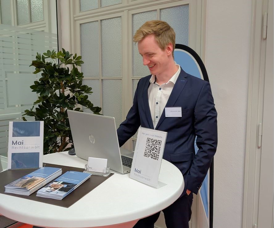 Rechtsanwalt Alexander Mai an seinem Messestand mit Kanzleiunterlagen